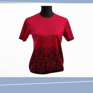 May include: A red short-sleeved shirt with a black floral pattern at the bottom.
