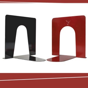 Pode incluir: Dois suportes de livros de metal, um preto e outro vermelho, são exibidos em um fundo branco. Cada suporte de livros tem uma forma retangular com um recorte curvo no centro e uma base plana. O suporte de livros vermelho tem um pequeno emblema.