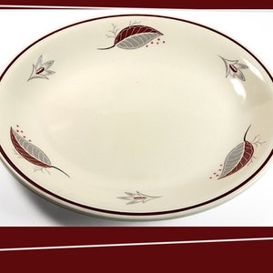 May include: A white oval serving platter with a red rim and a gray and red leaf design.