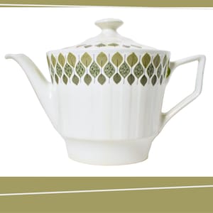Puede incluir: Tetera de cerámica blanca con tapa, con un diseño de hojas verdes y marrones en la parte superior. La tetera tiene un pico, un asa y un cuerpo acanalado. La tapa tiene un pequeño pomo.