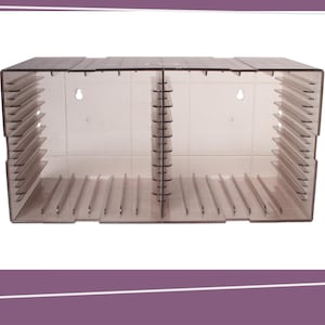 May include: A clear acrylic display case with multiple slots for organizing items. The case has a rectangular shape with a divided interior and a series of angled dividers. Two small holes are visible on the back panel for mounting.