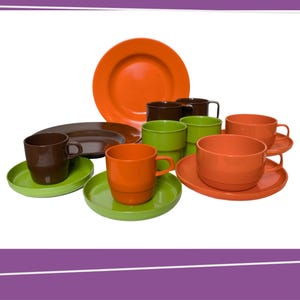 Puede incluir: Un conjunto de vajilla colorida de estilo retro. El juego incluye tazas, platillos y platos naranjas, marrones y verdes. Los platos son redondos y las tazas tienen asas. La vajilla está dispuesta sobre un fondo blanco.