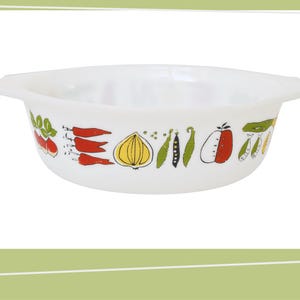 May include: White ceramic baking dish with a colourful vegetable design. The design features red carrots, green peas, a yellow onion, and a red tomato.