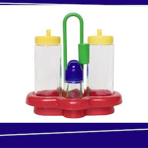 Op de afbeelding: Een rode plastic condimentenset met twee doorzichtige flessen met gele deksels en een blauwe zoutstrooier. De set bevat een groene handgreep en een rode basis.