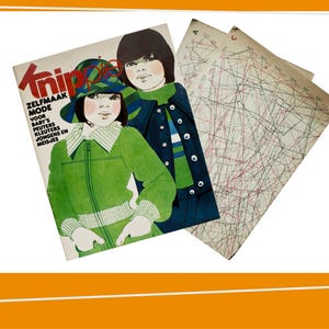 Può includere: Una copertina di rivista vintage con illustrazioni di bambini in abiti verdi e blu. La rivista si intitola "Knippie" con testo in olandese. Due fogli di modelli sono visibili sullo sfondo, con linee e segni colorati.