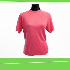 May include: A pink short-sleeved sweater with a round neckline.