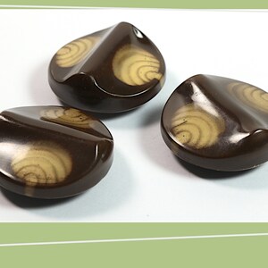 May include: Three brown plastic buttons with a swirl design in a lighter shade of brown.