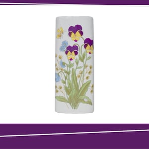 Op de afbeelding: Een witte keramische vaas met een bloemenontwerp. De vaas heeft paarse, gele en blauwe bloemen en een gele vlinder. De cilindrische vaas toont een gedetailleerde botanische illustratie.