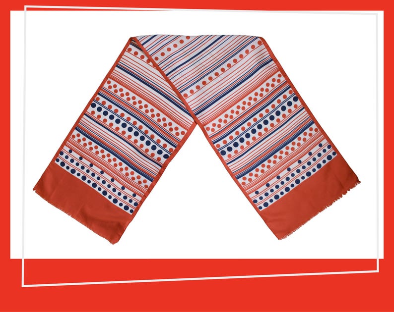 Pode incluir: Um len&ccedil;o vintage com um padr&atilde;o geom&eacute;trico arrojado. O len&ccedil;o apresenta listras e bolinhas em vermelho, branco e azul marinho sobre um fundo branco. As extremidades do len&ccedil;o s&atilde;o de cor laranja queimado s&oacute;lido com uma borda com franjas.