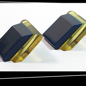 May include: A pair of vintage earrings with a geometric design. The earrings are made of blue and yellow plastic.