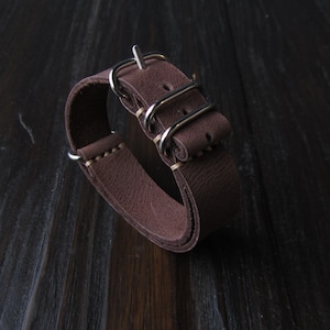 May include: A brown leather watch strap with a silver buckle and three keeper loops.