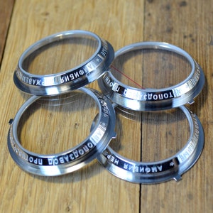 May include: Four silver watch bezels with clear glass inserts. The bezels are engraved with the words "AMPHORA", "TOMONOVA", "ПРОИЗВОДСТВО", and "ХКАБЕДОН".