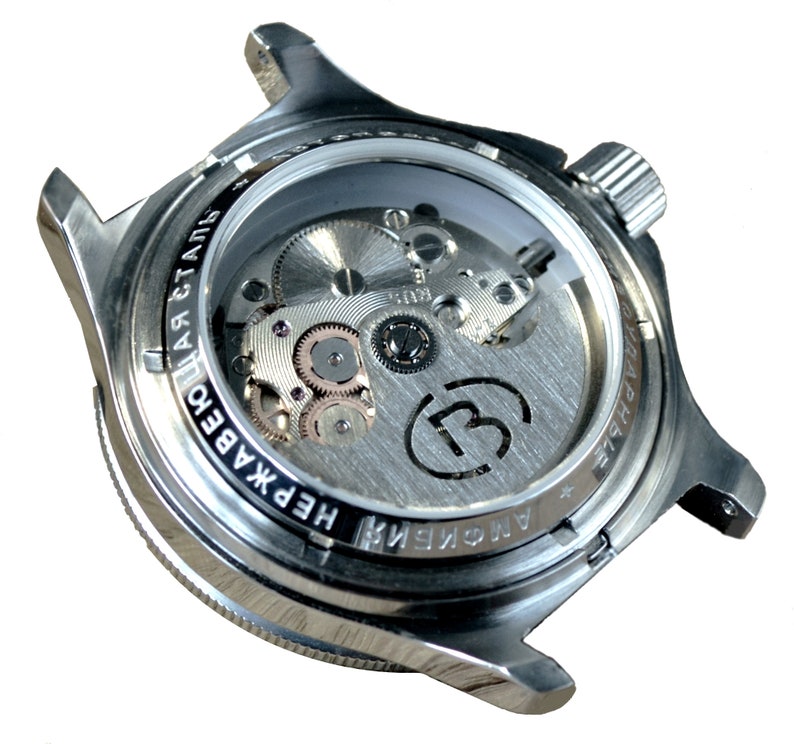 May include: A silver watch with a clear case back revealing the inner workings of the automatic movement. The watch face has the text "АВТОМАТИЧЕСКИЕ" and "НЕРЖАВЕЮЩАЯ СТАЛЬ" printed around the edge.