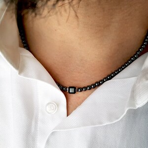 May include: A black beaded necklace with a square black pendant.