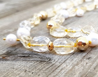 May include: A gold and white beaded necklace with clear and yellow faceted beads. The necklace is made with gold beads and pearls.