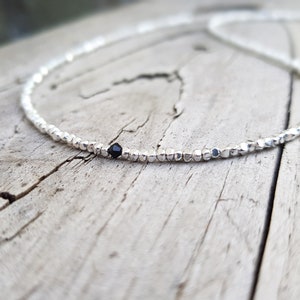 collana elegante e sottile, perfetta per uomo o donna, composta da pepite in argento solido ed al centro un piccolo cristallo in tre colori a scelta tra nero, verde smeraldo e blu zaffiro.