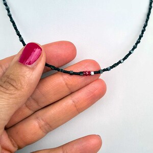 collana sottile ed elegante da uomo composta da pietre di ematite a forma di cubo  alternate con perline giapponesi di colore nero al centro tre pietre di rubino naturale