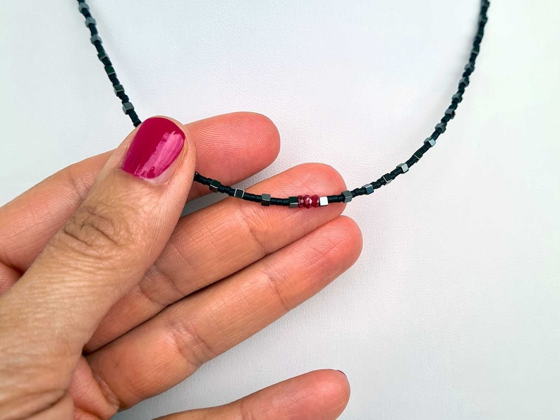 collana sottile ed elegante da uomo composta da pietre di ematite a forma di cubo  alternate con perline giapponesi di colore nero al centro tre pietre di rubino naturale