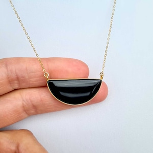 Pu&ograve; includere: Una collana con catena dorata e un ciondolo a forma di mezza luna nera.