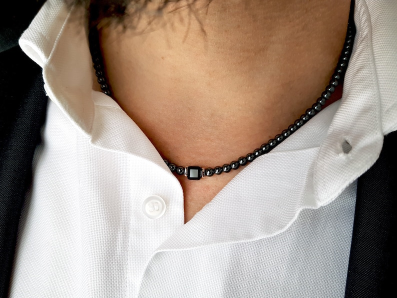 May include: A black beaded necklace with a square black pendant.