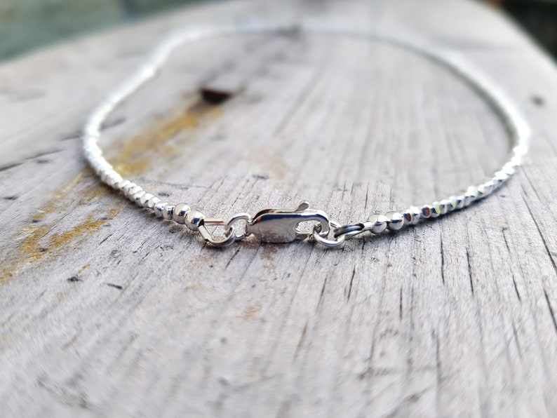 collana elegante e sottile, perfetta per uomo o donna, composta da pepite in argento solido ed al centro un piccolo cristallo in tre colori a scelta tra nero, verde smeraldo e blu zaffiro.