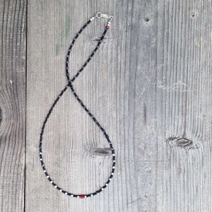 collana sottile ed elegante da uomo composta da pietre di ematite a forma di cubo  alternate con perline giapponesi di colore nero al centro tre pietre di rubino naturale