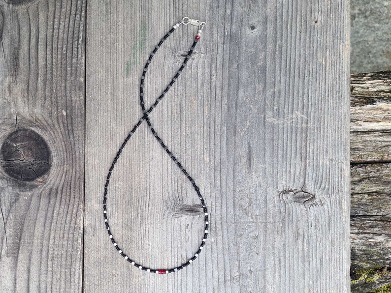collana sottile ed elegante da uomo composta da pietre di ematite a forma di cubo  alternate con perline giapponesi di colore nero al centro tre pietre di rubino naturale