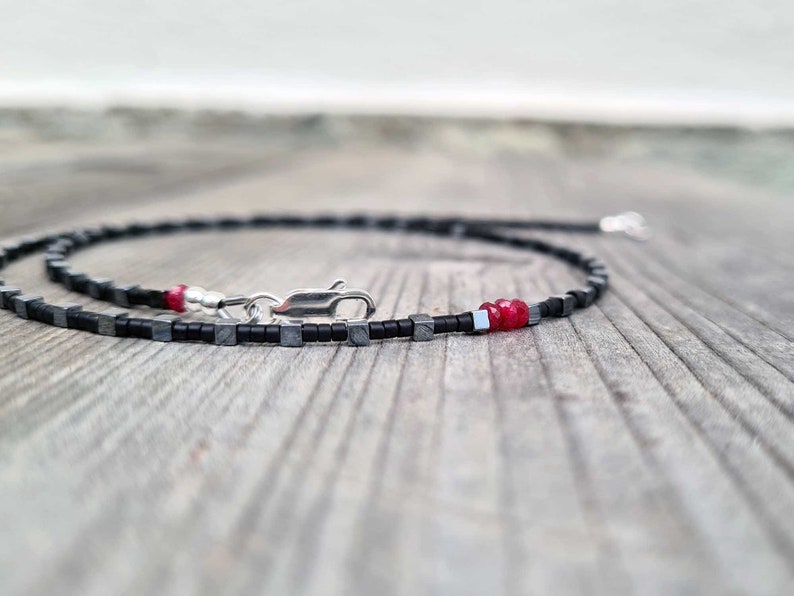 collana sottile ed elegante da uomo composta da pietre di ematite a forma di cubo  alternate con perline giapponesi di colore nero al centro tre pietre di rubino naturale