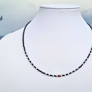 collana sottile ed elegante da uomo composta da pietre di ematite a forma di cubo  alternate con perline giapponesi di colore nero al centro tre pietre di rubino naturale