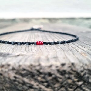 collana sottile ed elegante da uomo composta da pietre di ematite a forma di cubo  alternate con perline giapponesi di colore nero al centro tre pietre di rubino naturale