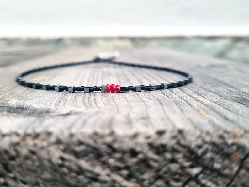 collana sottile ed elegante da uomo composta da pietre di ematite a forma di cubo  alternate con perline giapponesi di colore nero al centro tre pietre di rubino naturale