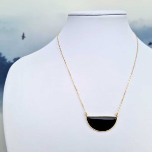 Pu&ograve; includere: Una collana con catena dorata e un ciondolo a forma di mezza luna nera.