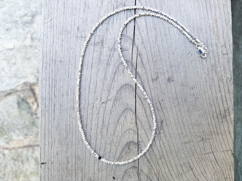 collana elegante e sottile, perfetta per uomo o donna, composta da pepite in argento solido ed al centro un piccolo cristallo in tre colori a scelta tra nero, verde smeraldo e blu zaffiro.