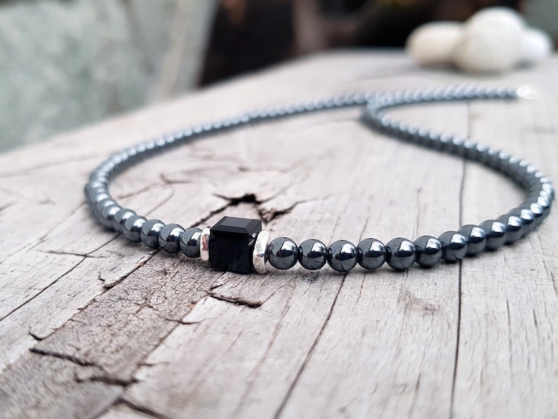 May include: A black hematite beaded necklace with a black square pendant.