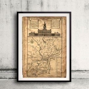 May include: Framed vintage map of Philadelphia and surrounding areas, featuring detailed illustrations of buildings and geographical features. The map is printed on aged paper and includes text at the top and along the right side. The map is in a black frame.