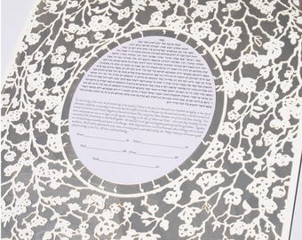 May include: A white and grey wedding ketubah with a floral design. The ketubah is a Jewish marriage contract and is often displayed in the home. The text on the ketubah is in Hebrew and English.