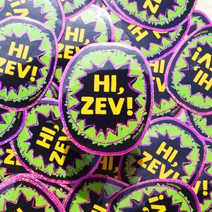 May include: A collection of oval stickers featuring a black center with the yellow text HI, ZEV! enclosed in a jagged lime green border. Each sticker is outlined with a thin, sparkling purple glitter edge and includes the small text @READ_RECEIPTS.