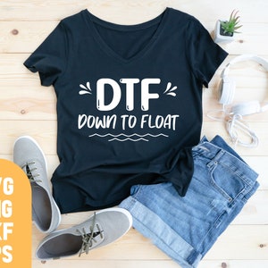 May include: A black t-shirt with a white graphic that says "DTF" and "Down to Float". The shirt is laid out on a wooden surface with a pair of gray sneakers, a pair of blue jeans, and a pair of white headphones.