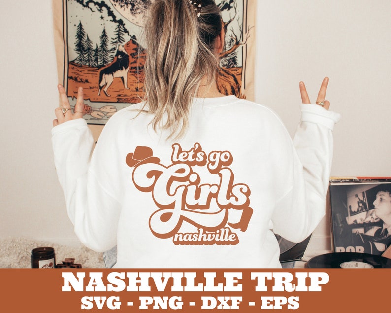 May include: A white sweatshirt with the text "Let's go girls Nashville" in brown lettering with a cowboy hat graphic.