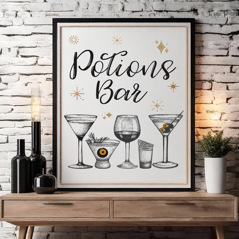 May include: A framed print with the words "Potions Bar" in elegant script, featuring illustrations of various cocktail glasses. Gold star and glitter accents adorn the white background. The print is displayed on a wooden table against a brick wall.