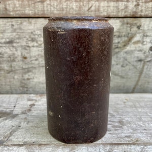 以下が含まれることがあります： わずかにざらざらした質感の濃い茶色の円筒形の木製ジャー。ジャーは白い縁と側面に白い斑点があります。