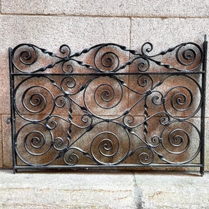May include: A black wrought iron gate with a decorative design of swirling scrolls. The gate is made of metal and has a traditional style.