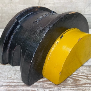 Könnte beinhalten: Eine schwarze und gelbe Holzhalbkuppel. Die schwarze Hälfte ist mit dem Wort "WATER" in weißen Buchstaben bemalt. Die gelbe Hälfte ist glatt und abgerundet.