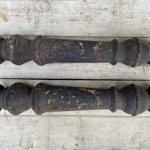 Puede incluir: Dos balaustres de madera marrón oscuro con un diseño torneado decorativo. Los balaustres están desgastados y tienen un acabado desgastado.