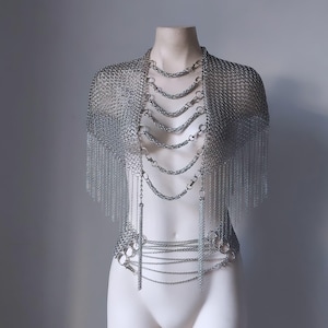 May include: A silver chainmail top with a fringe detail. The top is layered with multiple chains and has a matching chain belt.