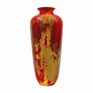 May include: A tall, decorative vase with a glossy finish. The vase features a striking color palette of red and gold, with a textured, mottled appearance. The vase has a slender, elongated shape with a flared top.