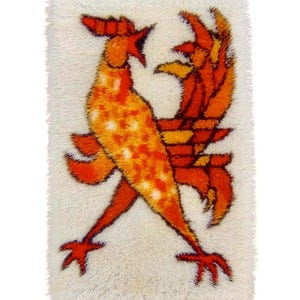 May include: A rectangular, shag rug featuring a stylized design of two roosters facing each other. The roosters are rendered in shades of orange and yellow against a white background. The rug has a soft, textured appearance.