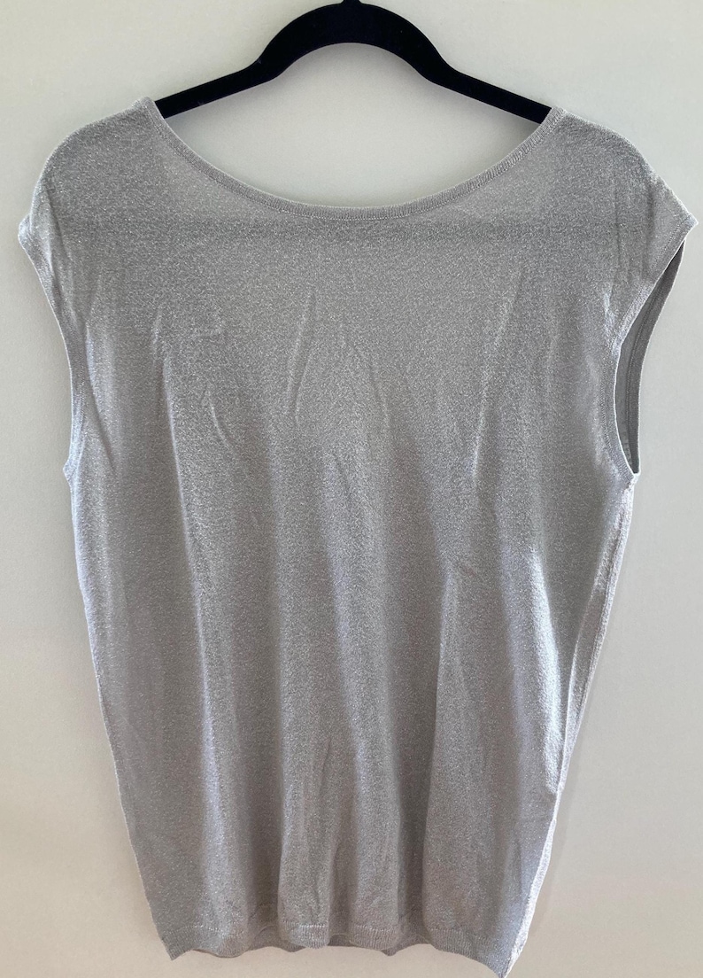May include: A sleeveless, light gray, sparkly top with a scoop neck.