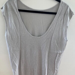 May include: A light gray sleeveless top with a scoop neck.