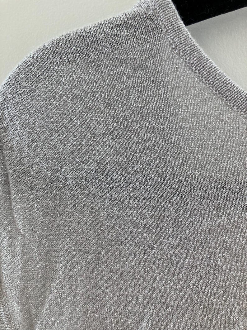 May include: A close-up of a silver knit fabric with a fine, even weave.